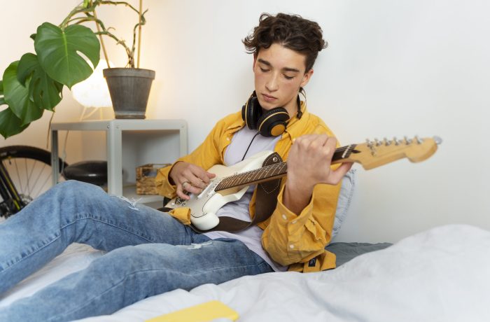 boy-playing-guitar-home-side-view