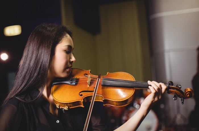 Female student playing violin in a studio