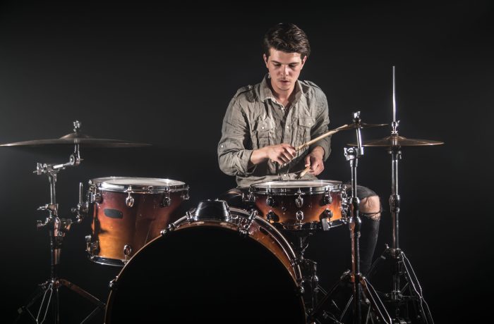 Professional drummer playing on drum set on stage on the black background with drum sticks and vintage look. Top view. Smoke effect